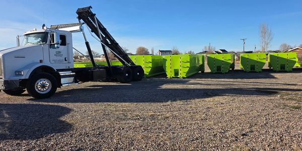 Patriot Solutions truck beside bright green roll-off dumpsters
